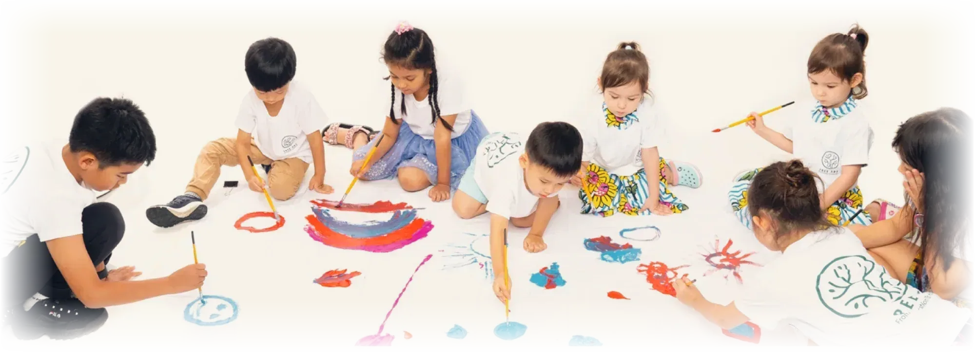 OpenKids 小画家们围坐在画室地面上,一起在大画布上创作