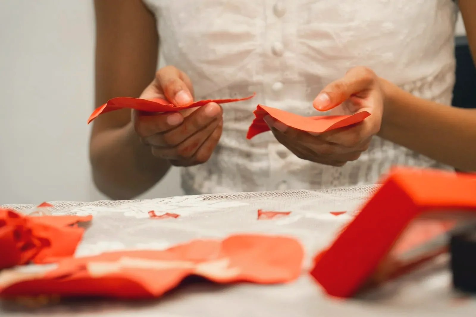 Hands folding a sheet of red paper
