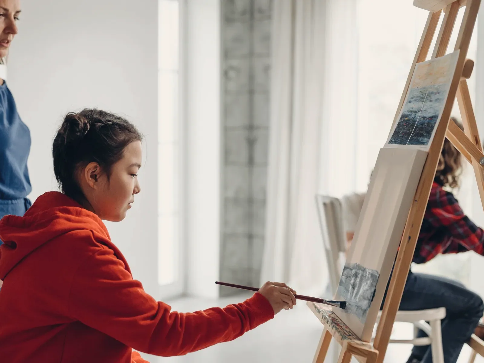 A young girl at an easel, absorbed in her painting