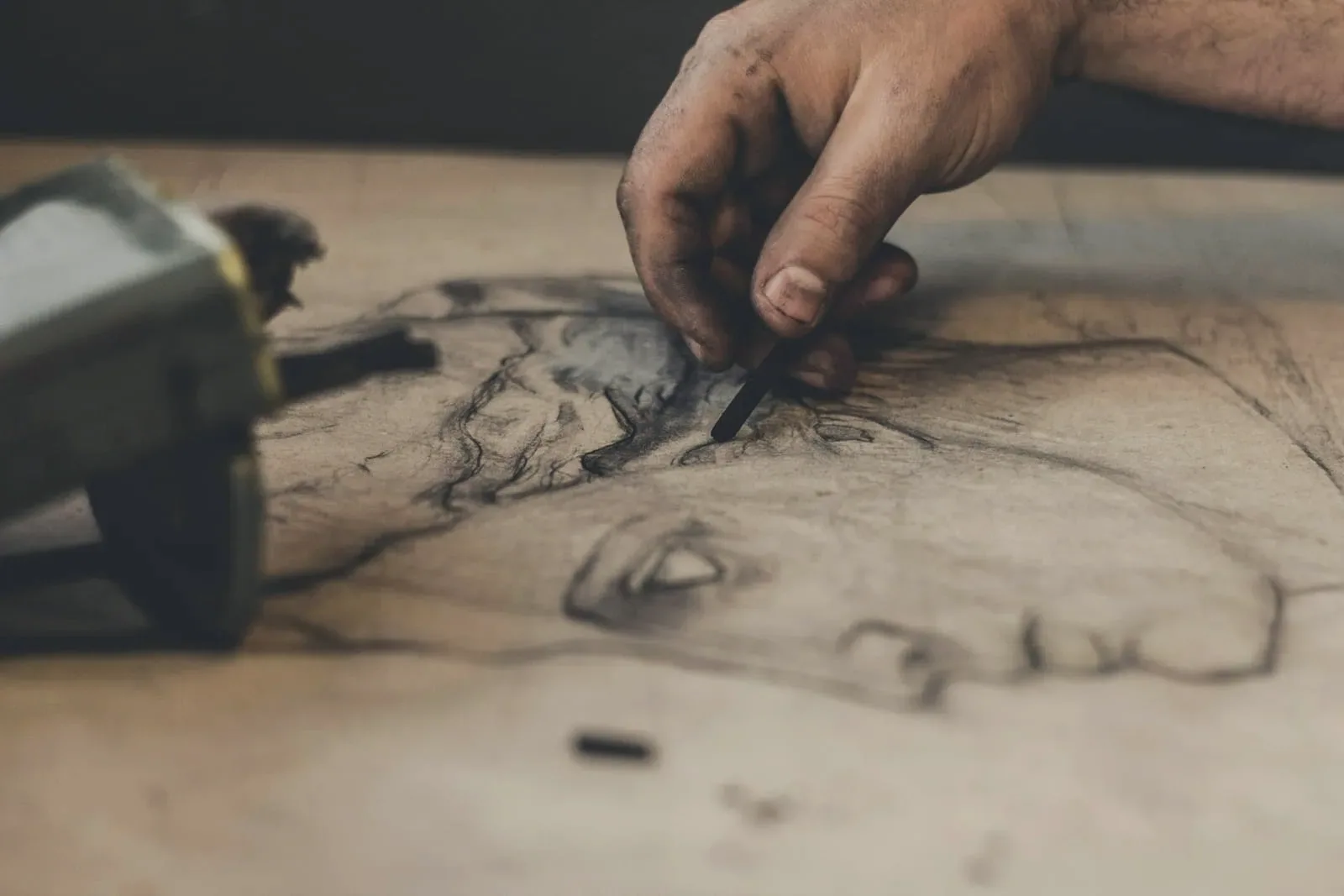 A hand shading a charcoal portrait study