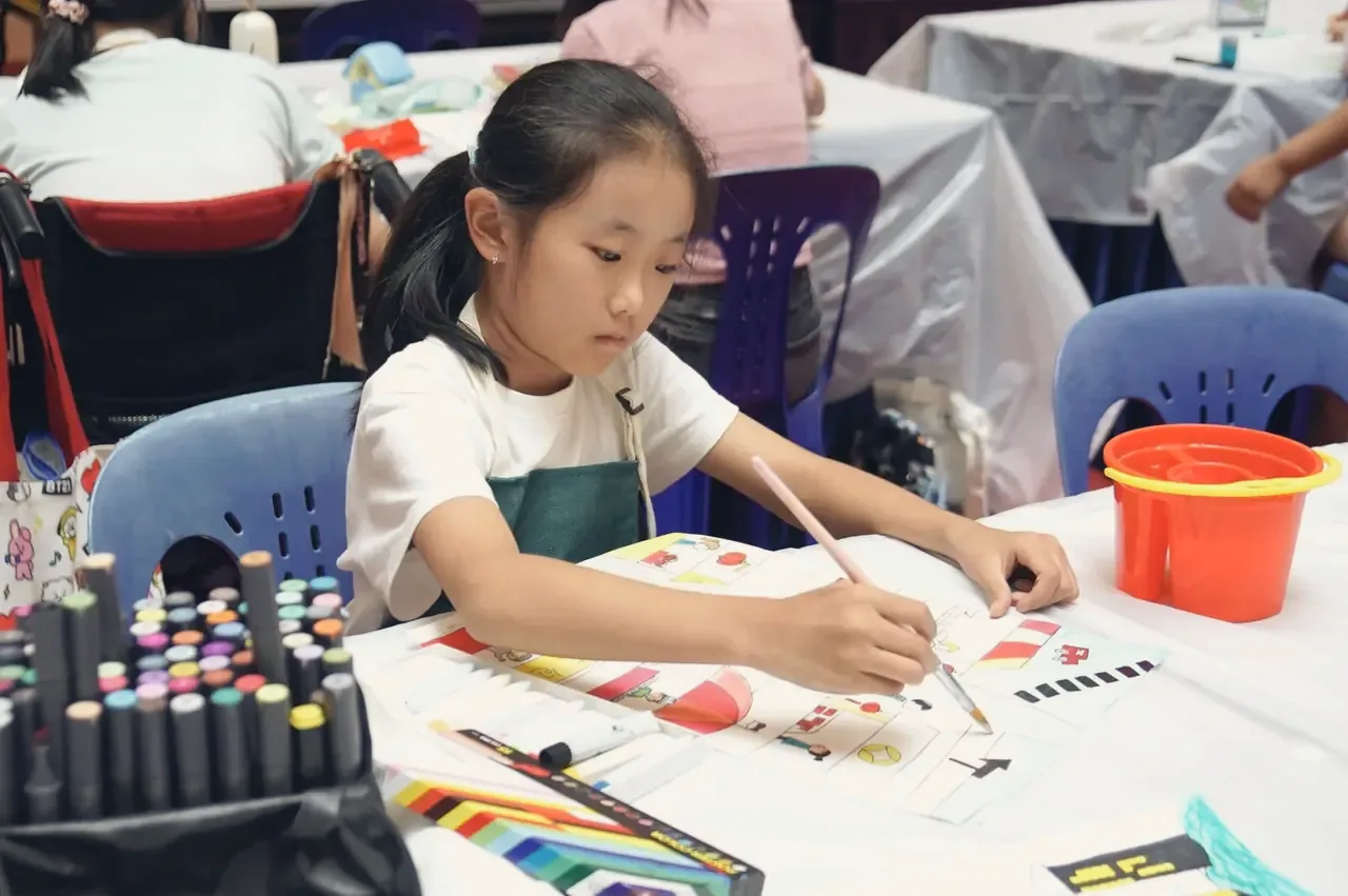 A girl deep in concentration, painting at a studio table