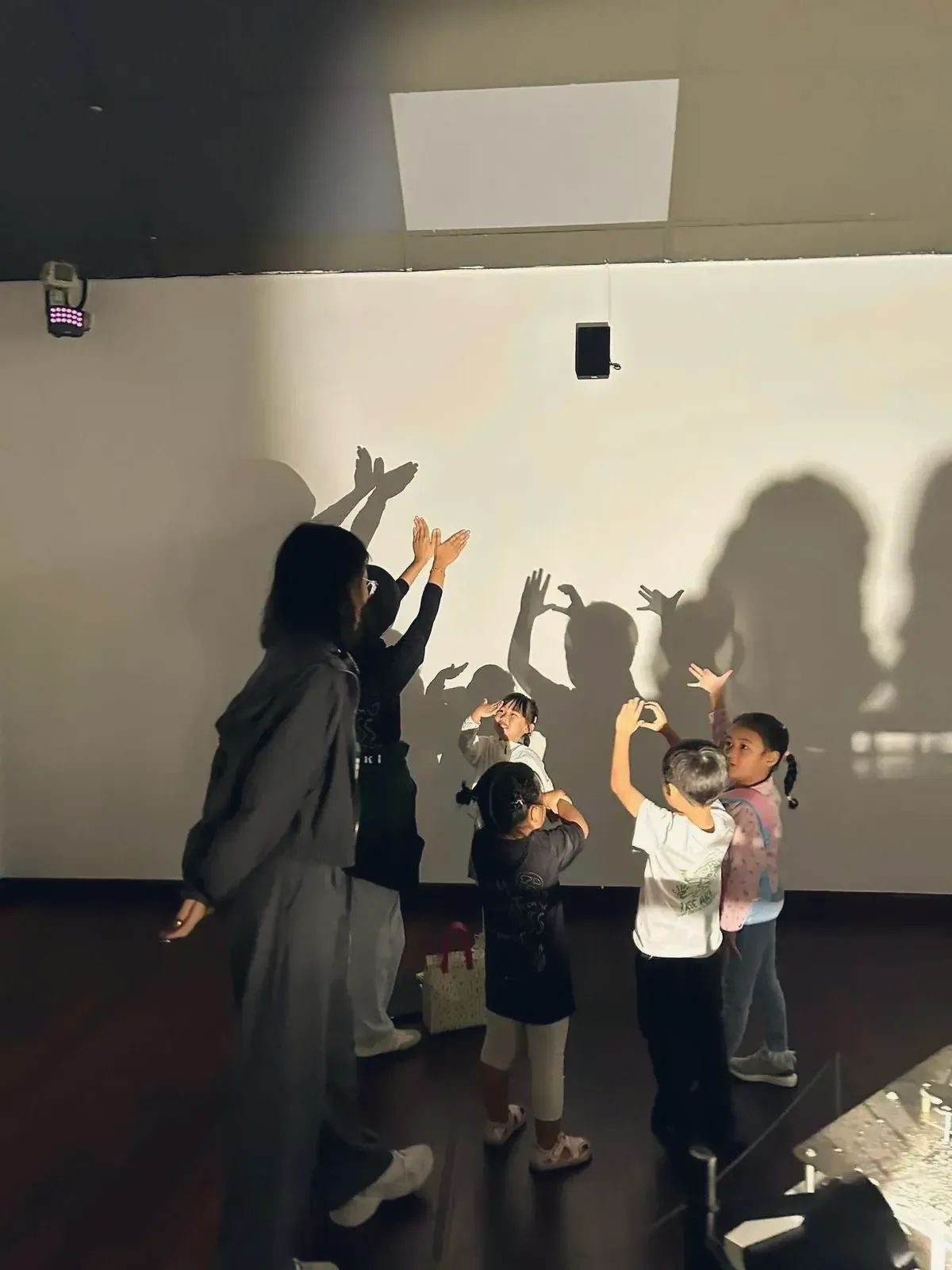 OpenKids 美术课上,老师和孩子们在发光的墙上投出手影