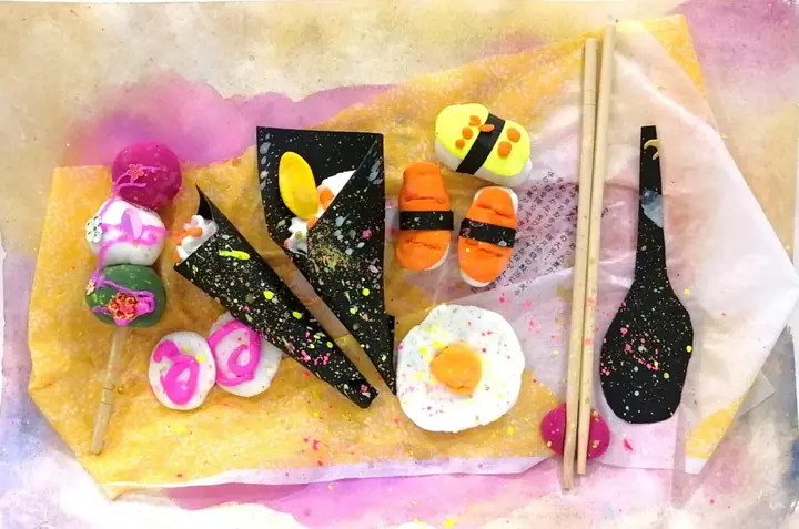 A clay sushi bento with dango skewers, hand rolls and rolled omelette