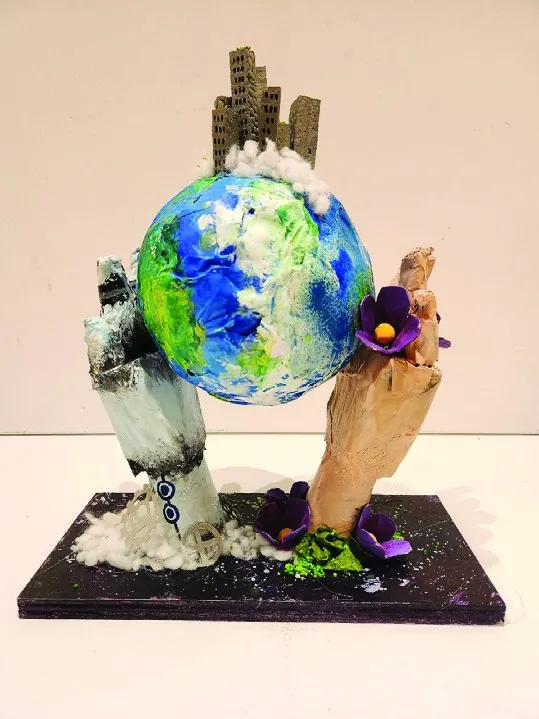 A mixed media sculpture of two hands holding up a painted globe