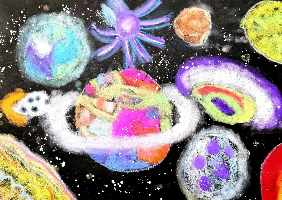 Glowing ringed planets, a star and a small rocket drawn in soft pastel on black paper