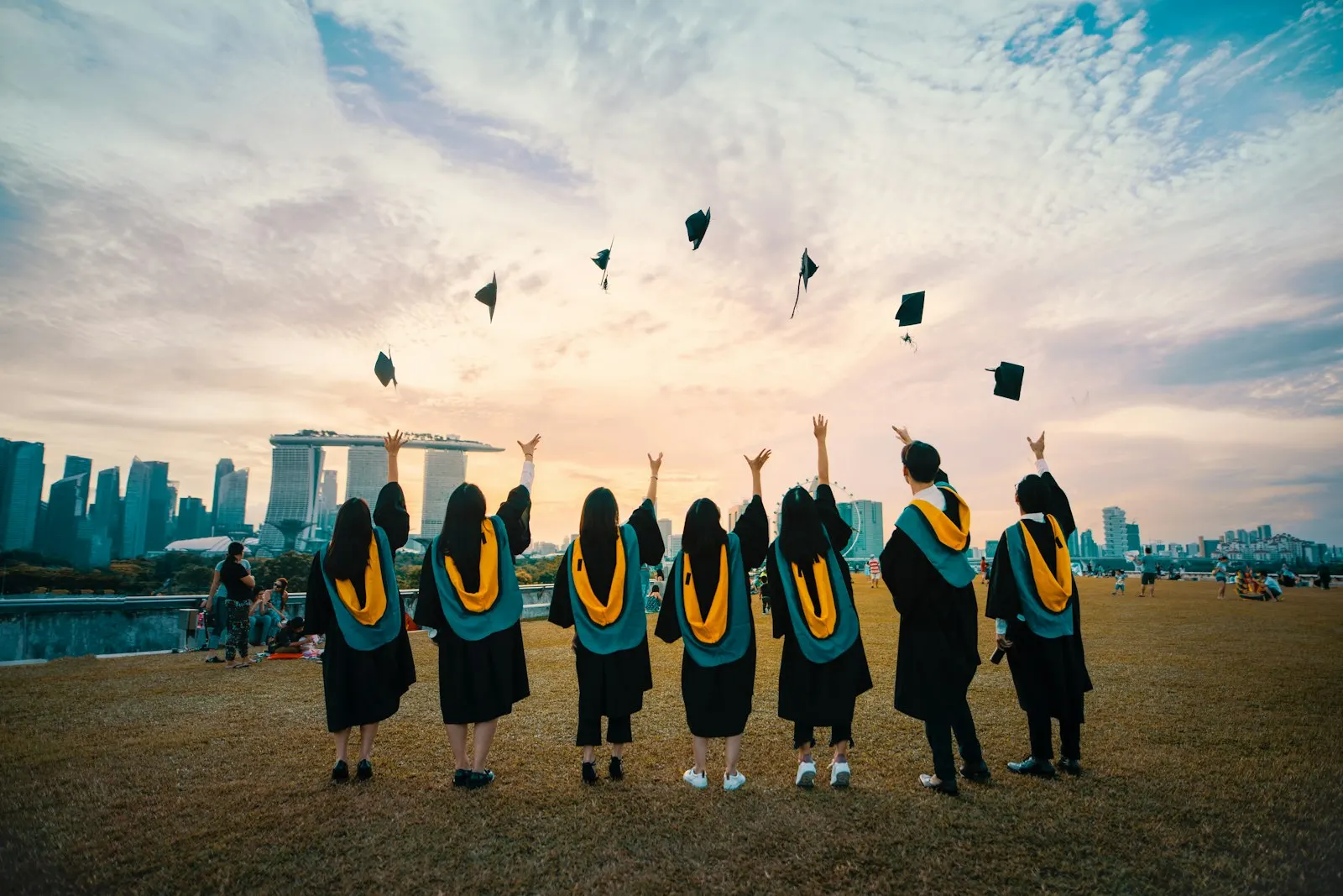 Graduates throwing their caps against the Singapore skyline