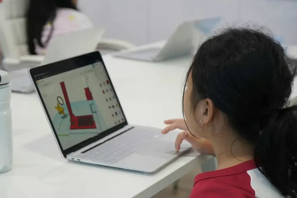 A girl, seen from behind, builds a 3D model on a laptop