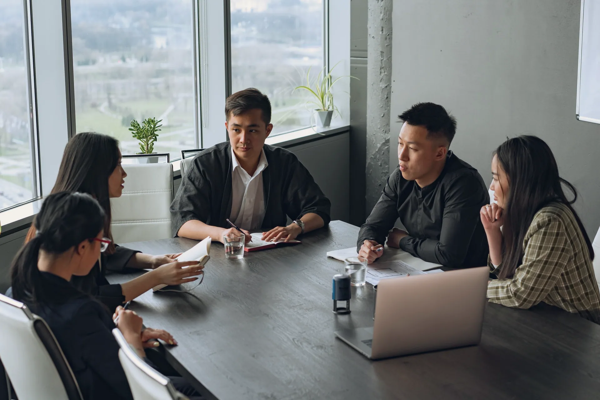 A team going through papers around a meeting-room table by tall windows