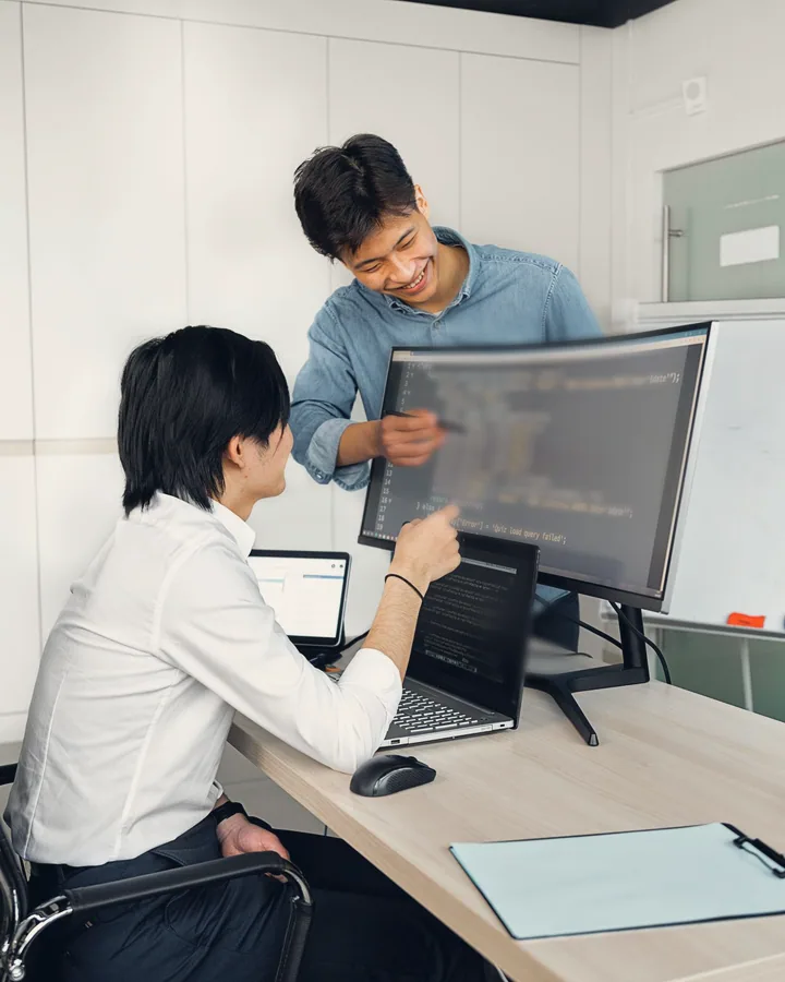 A mentor and a young coder going through the work on a screen together