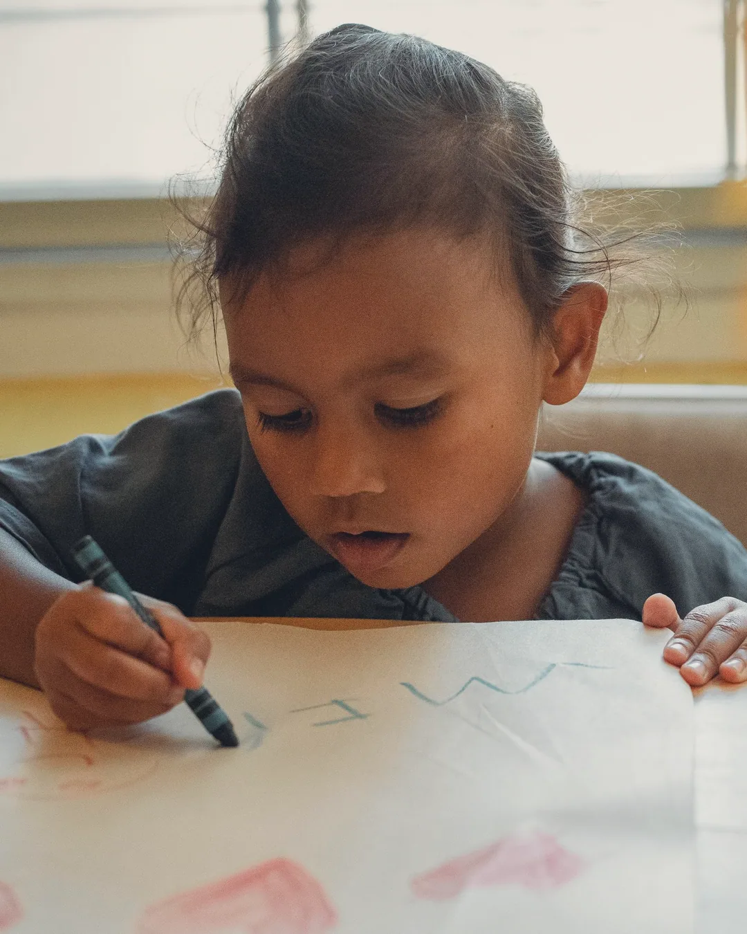 小小孩握着蜡笔在大纸上画画