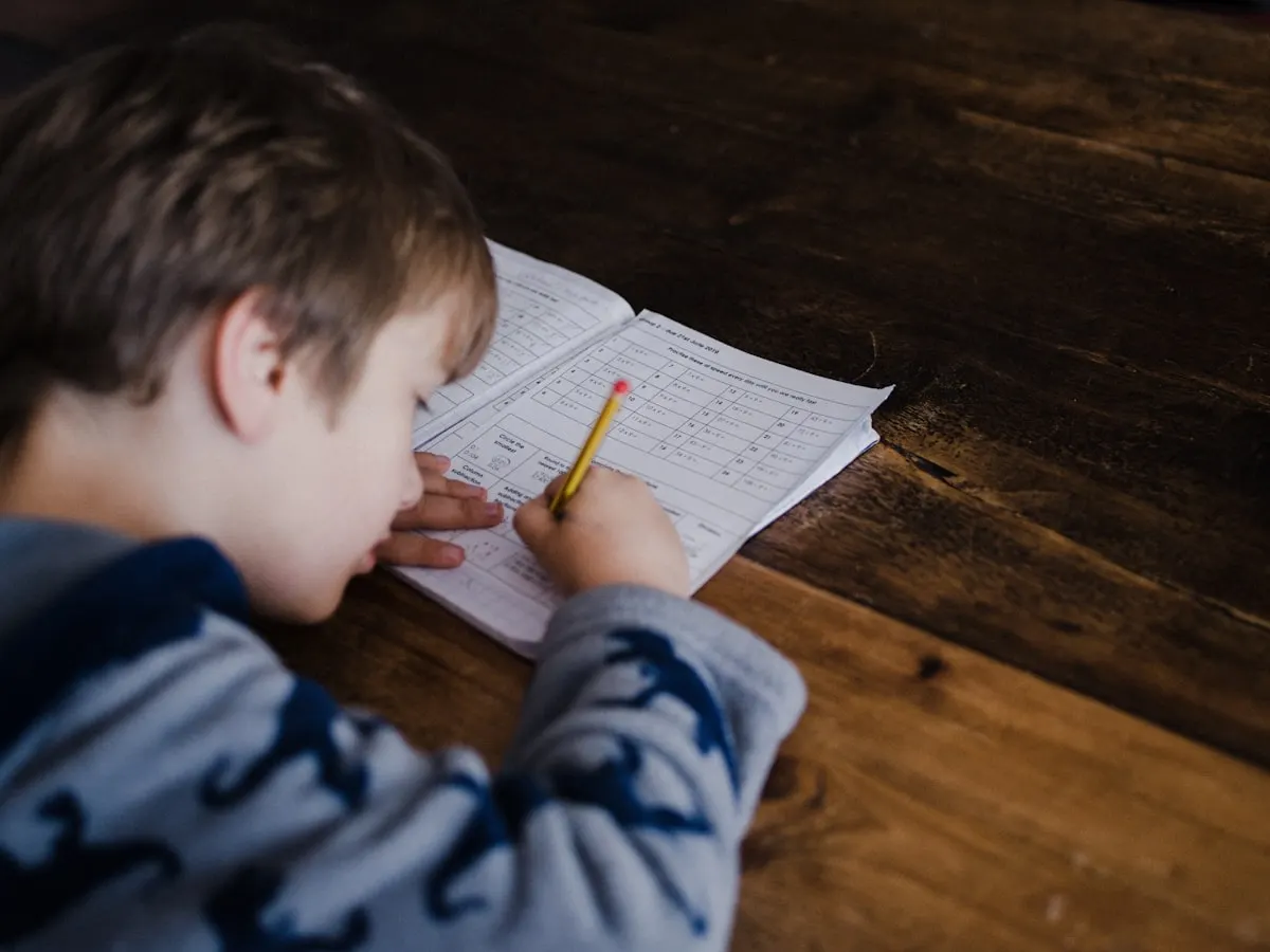 A young boy focused on his workbook